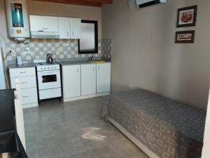 eine kleine Küche mit weißen Schränken und einem Bett darin in der Unterkunft Los Pinares de Belgrano in Gualeguaychú