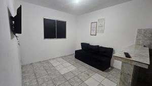 a living room with a black couch and a table at Casa com 2 Quartos e Garagem, Alto da Cruz, Camaçari in Camaçari