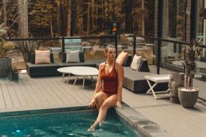 a woman sitting on the edge of a swimming pool at Zen House 4 - Villas & Spa in Morin Heights +83 photos