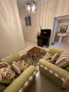 a living room with two green couches and a piano at Güzellik Junior Suite جناح قوزيوليك in Abha