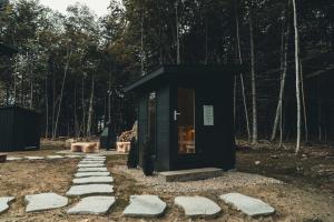 a small black building with stepping stones in a forest at Zen House 6 - Villas & Spa in Morin Heights