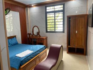 a small bedroom with a bed and a chair at Khách sạn Trung Hoa in Ấp Bàu Bàng