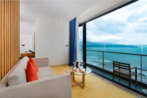 a living room with a couch and a view of the ocean at Sala Danang Beach Hotel in Danang