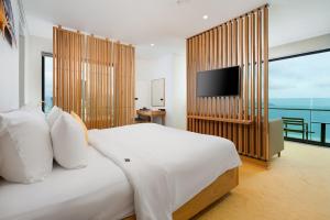 a bedroom with a large white bed and a television at Sala Danang Beach Hotel in Danang