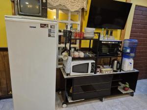 a kitchen with a microwave and a tv on a cart at Hostal Oasis in Puerto Natales +12 photos