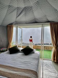 een vrouw in een slaapkamer die uit het raam kijkt bij ชาเลต์ ภูทับเบิก in Ban Maeo Thap Boek