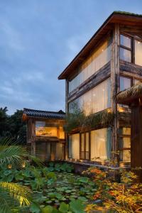 een huis met een vijver ervoor bij Meilanmeilv Forest Luxe Inn-Chengdu Sansheng Township Branch in Ta-mien-chen