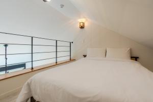 Un dormitorio con una cama blanca y un balcón. en Trip Recipe, en Sinŏm-ni