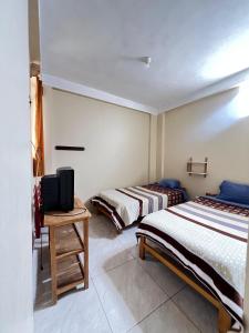 a bedroom with two beds and a tv on a table at Curahuasi Backpackers in Curahuasi