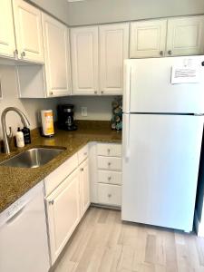 a kitchen with white cabinets and a white refrigerator at Welcoming 2-bedroom condo with bonus room! in Indian Shores