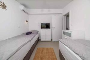 een witte slaapkamer met 2 bedden en een televisie bij Holiday home in Selce 54575 in Selce +27 foto's
