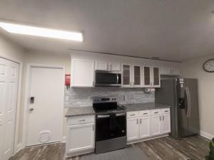 a kitchen with white cabinets and a black refrigerator at Serene Sunshine State Escape in Deltona