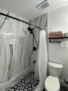 a white bathroom with a toilet and a shower at Cozy Retreat Near EWR with NYC access in Newark