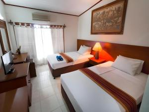 a hotel room with two beds and a desk at Maha Jaya Hotel Bali in Denpasar +6 photos