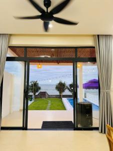 d'un salon avec un ventilateur de plafond et une vue sur l'océan. dans l'établissement Villa sát biển, 6pn, 9 giường, 7 toilet, hồ bơi riêng, bãi biển, sân vườn, à Tiến Thành