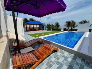 - deux chaises et un parasol à côté de la piscine dans l'établissement Villa sát biển, 6pn, 9 giường, 7 toilet, hồ bơi riêng, bãi biển, sân vườn, à Tiến Thành