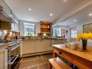 a large kitchen with white cabinets and a wooden table at 5 Bed in Threlkeld SZ270 in Threlkeld