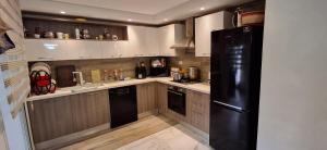 a kitchen with a black refrigerator and wooden cabinets at Modern & Comfortable Apartment in Aouina in El Aouina Station