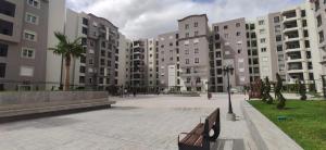 a park with buildings and a bench and palm trees at Modern & Comfortable Apartment in Aouina in El Aouina Station