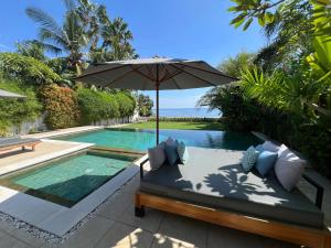 een patio met een parasol en een zwembad bij Villa Serenity Beachfront Bali in Pengastulan