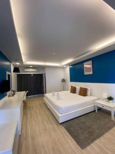 a bedroom with a large white bed and a blue wall at Curve Boutique Hotel in Pattaya Central