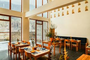 a restaurant with wooden tables and chairs and large windows at Mountain Lodges of Nepal Manang in Manangbhot