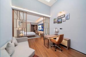 a living room with a couch and a desk and a bed at Days Hotel Guangzhou Haizhu in Guangzhou