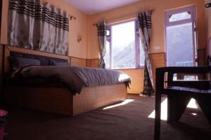 a bedroom with a bed and a large window at Madhurvi baker's and homestay in Chitkul +12 photos