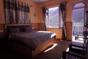 a bedroom with a bed and a large window at Madhurvi baker's and homestay in Chitkul