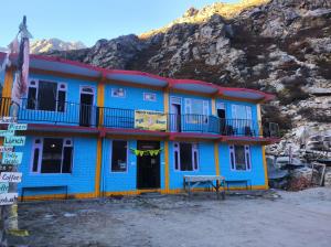 a blue and yellow building with a mountain in the background at Madhurvi baker's and homestay in Chitkul