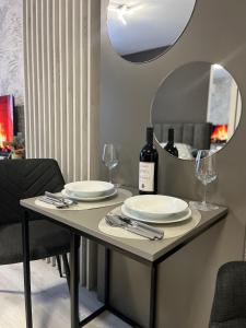 a table with plates and wine glasses and a mirror at Apartman Elite Stay Doboj in Doboj