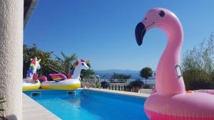 einen Pool mit aufblasbaren Flamingos und einem rosa Flamingo-Schwimmer in der Unterkunft Apartments in Lovran 15143 in Lovran + 7 Fotos