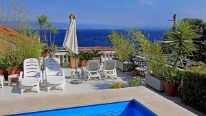 eine Terrasse mit Stühlen, einem Sonnenschirm und einem Pool in der Unterkunft Apartments in Lovran 15143 in Lovran