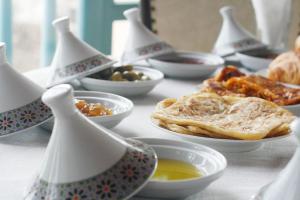 une table recouverte de bols de nourriture et de assiettes de nourriture dans l'établissement Riad Kafila, à Essaouira