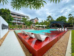 een zwembad met witte ligstoelen naast een gebouw bij Thai Fight Hotel in Lamai
