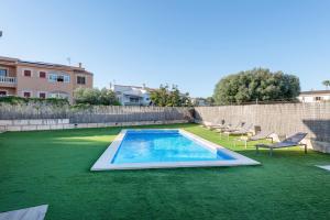 a swimming pool with lounge chairs on a green lawn at Cas Fraus in Sa Coma