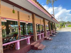 a row of tables and benches outside of a building at ปลาตอง รีสอร์ท in Chao Lao Beach