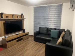 a living room with a black leather couch and a television at Arisbeth V in Panama City