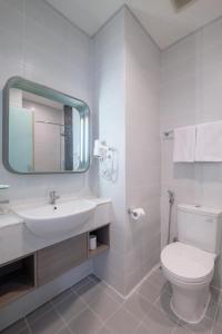 a bathroom with a toilet and a sink and a mirror at Swiss-Belexpress Jemursari in Surabaya