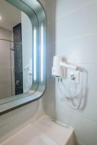 a bathroom with a mirror and a white sink at Zest Jemursari by Swiss-Belhotel International in Surabaya