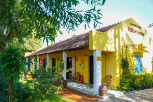 une maison jaune avec des chaises dans la cour dans l'établissement Lumiere Family Village Đông Tác, à Hiếu Xương