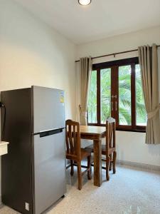 a kitchen with a refrigerator and a table with chairs at The Rinya Hotel Koh Phangan in Thong Sala