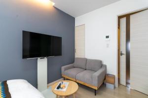 a living room with a couch and a flat screen tv at Rubens Hakata -ルーベンス博多- in Fukuoka