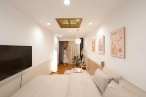 a white bedroom with a bed and a tv at Whole House with 3 Bedrooms in Hoan Kiem - 7mins to Hoan Kiem lake - FREE launchdry & breakfast in Hanoi