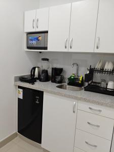 a kitchen with white cabinets and a black dishwasher at Habitacion con entrada independiente y aire acondicionado, Centro Piura in Piura +10 photos