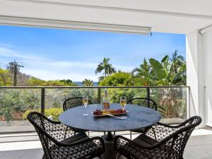 a table with two glasses of wine on a balcony at Oceanbreeze - Sunshine Beach Ocean Views in Sunshine Beach +13 photos