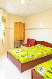 a bedroom with two beds with a green blanket at Thanh Bình Hostel in Can Tho