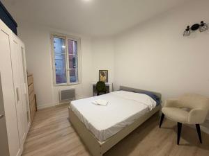 une chambre blanche avec un lit et une chaise dans l'établissement Appartement chic et moderne au cœur du mythique Marché des Antiquités, à Saint-Ouen