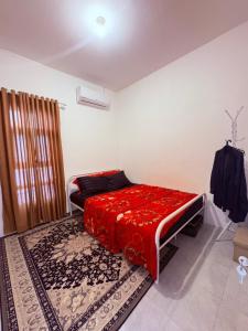 a bedroom with a red bed and a rug at Fortune Homestay Banyuwangi in Banyuwangi