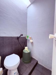 a bathroom with a toilet and a green trash can at Fortune Homestay Banyuwangi in Banyuwangi